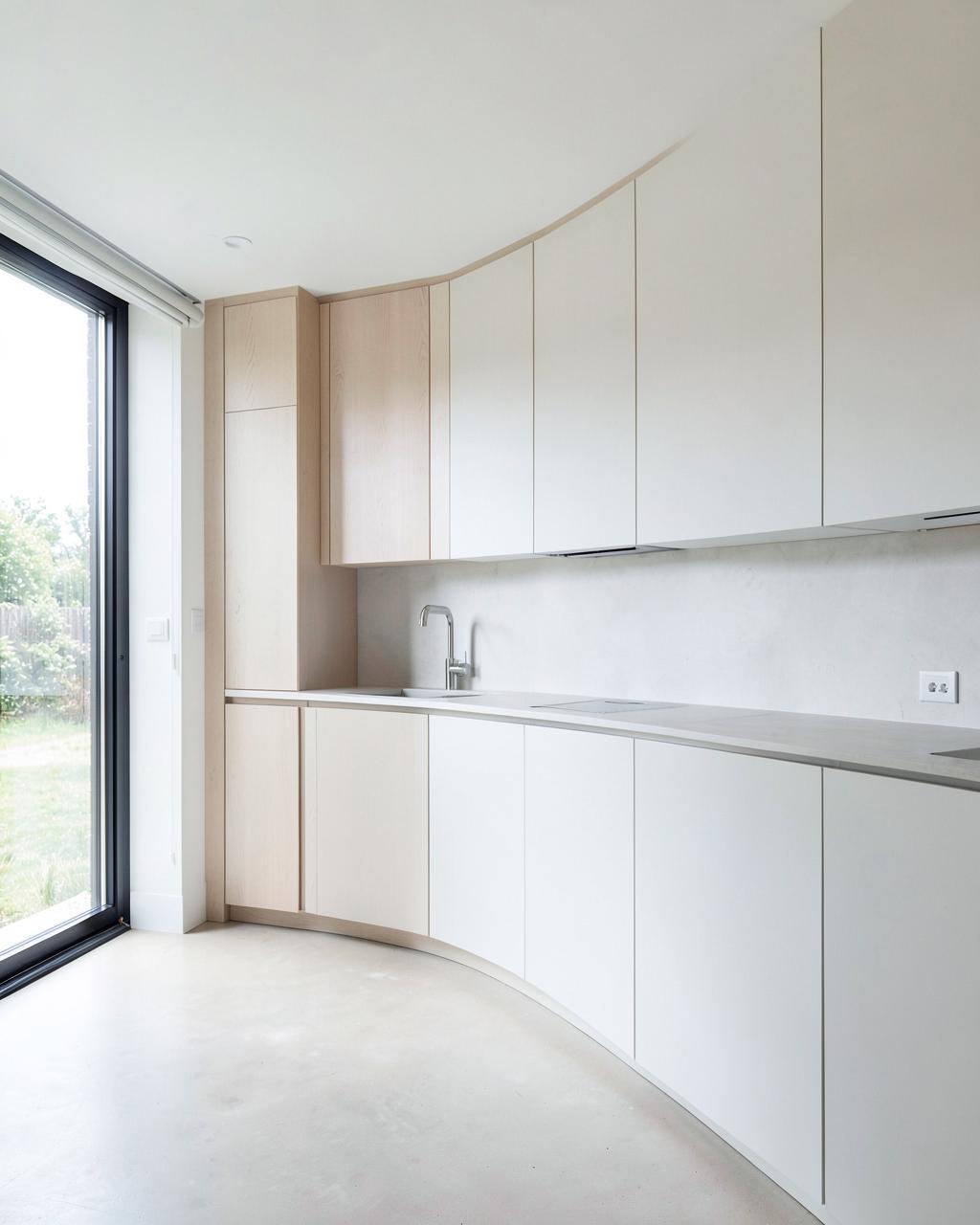Bright minimalist renovated open kitchen with pale oak and matte white cabinetry